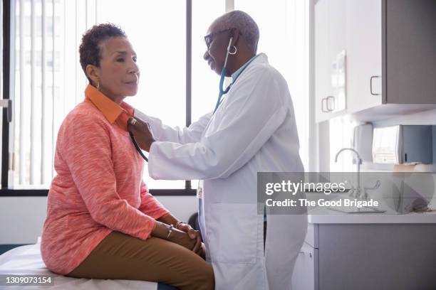 smiling female doctor examining senior patient in hospital - arzt untersuchung stock-fotos und bilder