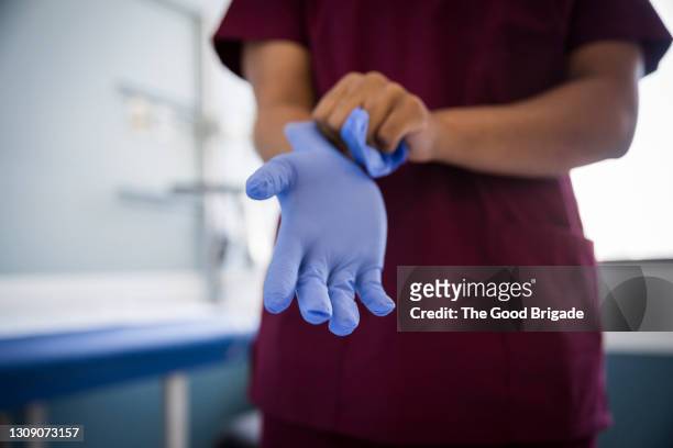 midsection of female nurse wearing protective gloves in hospital - guante fotografías e imágenes de stock