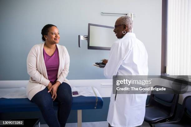 smiling senior doctor talking to female patient in hospital - examination room fotografías e imágenes de stock