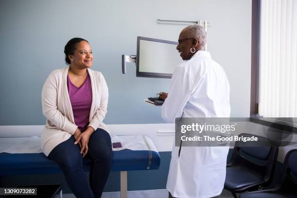 smiling senior doctor talking to female patient in hospital - doctor patient bildbanksfoton och bilder