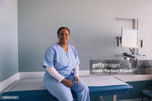 portrait of nurse sitting on exam table in hospital - doctor sitting stock pictures, royalty-free photos & images