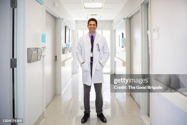 portrait of smiling doctor standing in hospital corridor - hände in den taschen stock-fotos und bilder