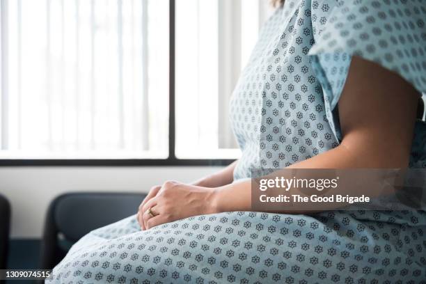 midsection of female patient waiting in hospital exam room - tavolo da visita foto e immagini stock