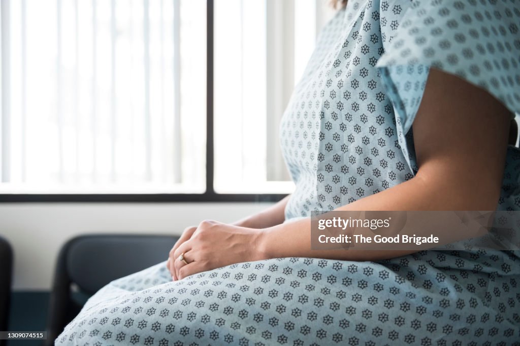 Midsection of female patient waiting in hospital exam room