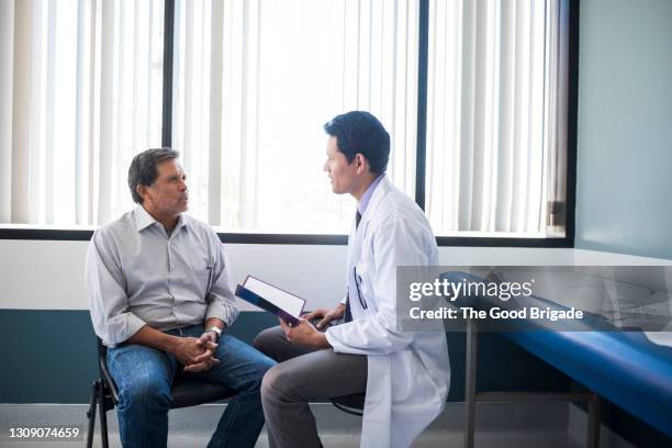 side view of doctor talking with senior patient in hospital - man talking to doctor bildbanksfoton och bilder