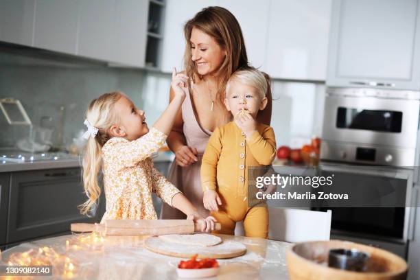 young woman with a boy and a girl playing, having fun in the kitchen, baking a pie. happy family with children - blond women happy eating stock pictures, royalty-free photos & images