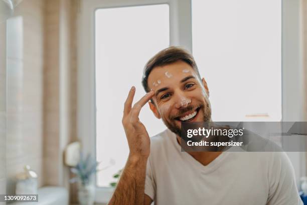 beautiful young man getting ready in the morning - face cream stock pictures, royalty-free photos & images