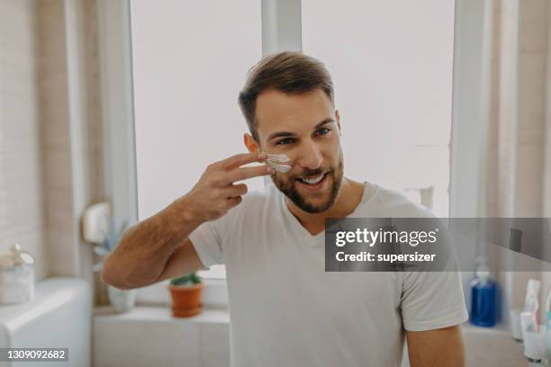 schöner junger mann immer bereit am morgen - gesichtscreme stock-fotos und bilder