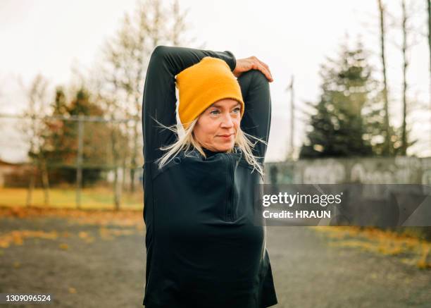 jogger faisant des étirements de bras le matin - sport hiver photos et images de collection