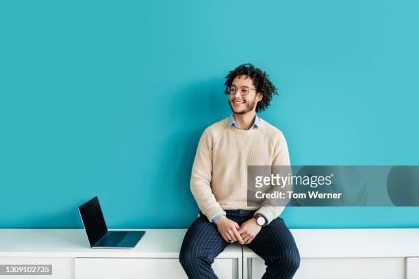 cheerful office employee sitting on cabinet smiling - lässig schicker stil stock-fotos und bilder