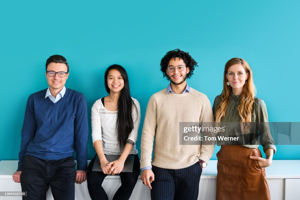 Portrait Of Office Colleagues Standing In Front Of Partition Wall