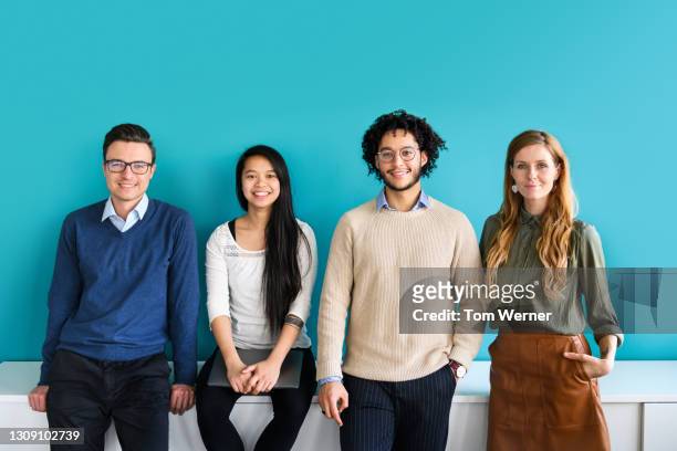 portrait of office colleagues standing in front of partition wall - four people stock-fotos und bilder
