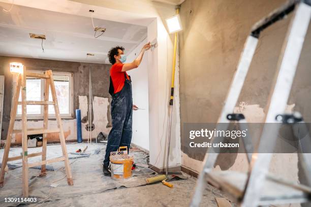 plâtrage et lissage de murs en béton par des ouvriers de la construction - maçon photos et images de collection