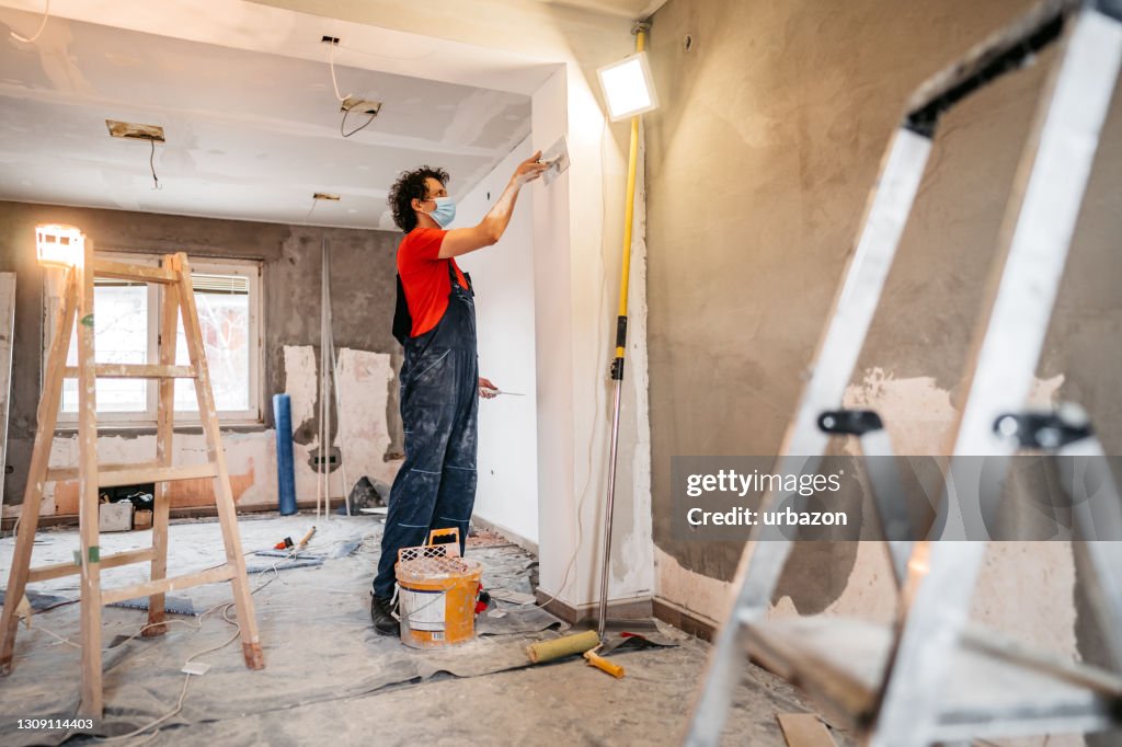 Construction worker plastering and smoothing concrete wall