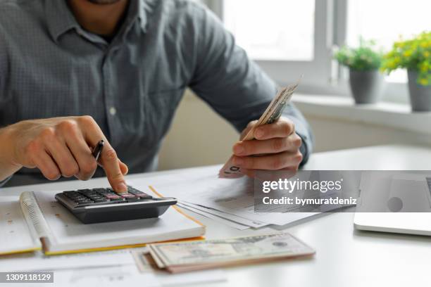 homme utilisant la calculatrice - billet de banque photos et images de collection