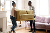 Young happy african american couple moving and carry table.