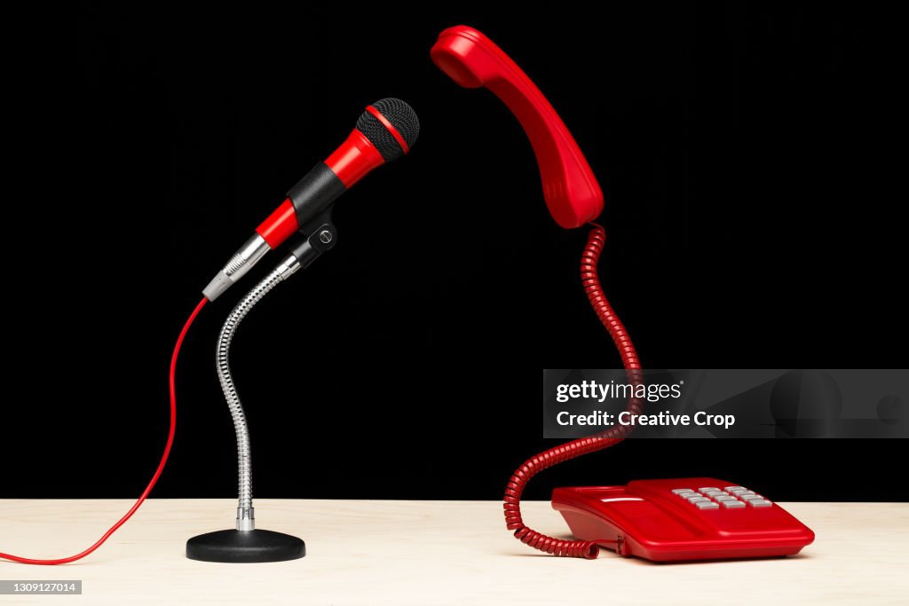 A telephone and microphone facing each on a desktop