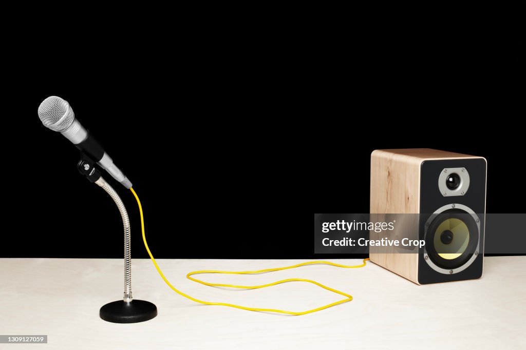 Microphone in a desktop stand connecting to a speaker on a tabletop