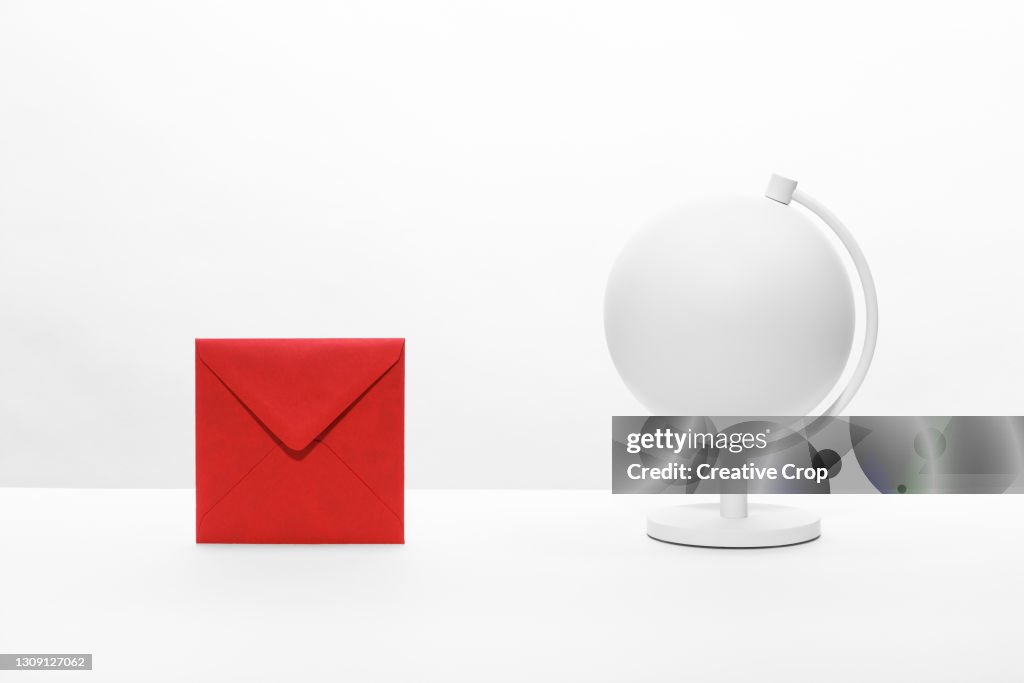 An envelope on a desktop next to a desk globe