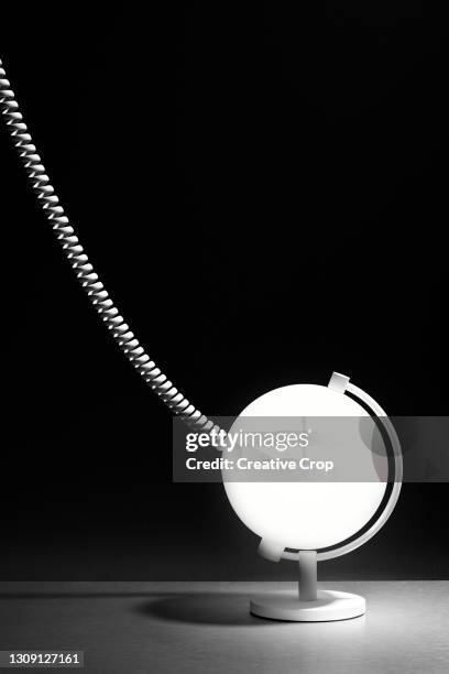 a curly cable attached to a white globe against a black background - microzoa stock pictures, royalty-free photos & images