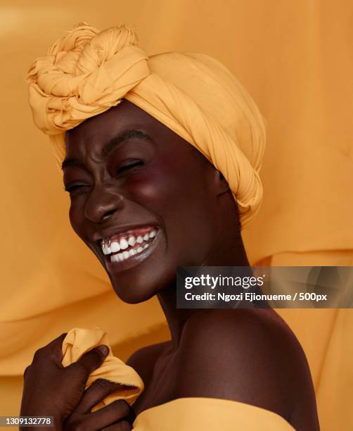 portrait of smiling young black woman wearing yellow headscarf,lagos,lagos,nigeria - blusher stock-fotos und bilder