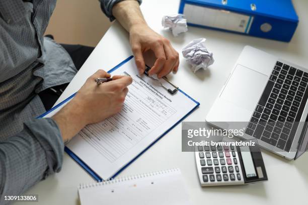 man using an unemployment benefits claim form - unemployment benefits stock pictures, royalty-free photos & images