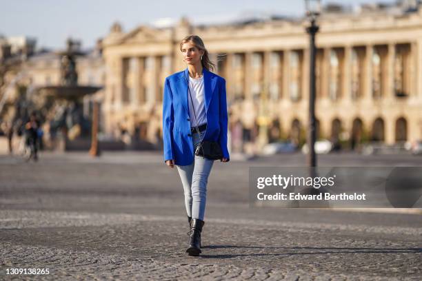 Xenia Adonts wears earrings, a bold blue oversized blazer jacket from Margiela, a white t-shirt from RTA, a black leather pouch bag from Bottega...