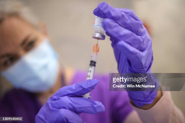Nurses draw vaccine doses from a vial as Maryland residents receive their second dose of the Moderna coronavirus vaccine at the Cameron Grove...