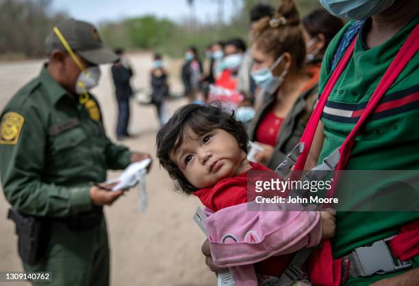 Karli, 4 months, waits with her family for transport by U.S. Border Patrol agents after their group of immigrants crossed the Rio Grande into Texas...