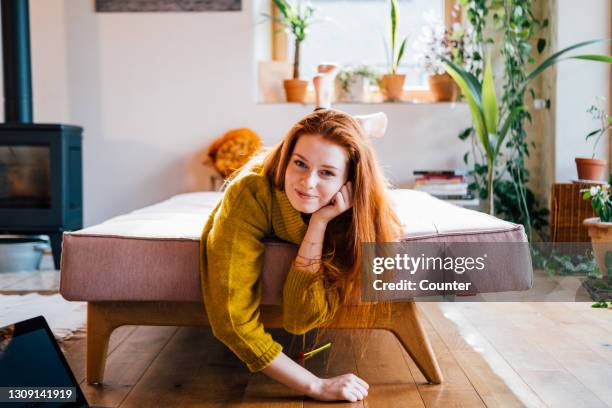 portrait of smiling woman with red hair on sofa - at home portrait stock pictures, royalty-free photos & images