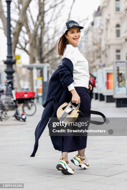 Model and DJane Gitta Saxx wearing a white sweater pullover by Sonja Kiefer Studio, a dark blue wrap skirt by Sonja Kiefer Studio, a dark blue and...