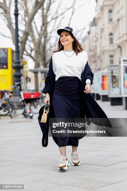 Model and DJane Gitta Saxx wearing a white sweater pullover by Sonja Kiefer Studio, a dark blue wrap skirt by Sonja Kiefer Studio, a dark blue and...