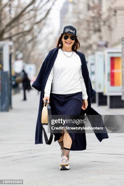 Model and DJane Gitta Saxx wearing a white sweater pullover by Sonja Kiefer Studio, a dark blue wrap skirt by Sonja Kiefer Studio, sunglasses by...