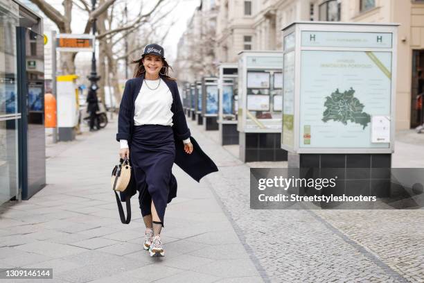 Model and DJane Gitta Saxx wearing a white sweater pullover by Sonja Kiefer Studio, a dark blue wrap skirt by Sonja Kiefer Studio, a dark blue and...