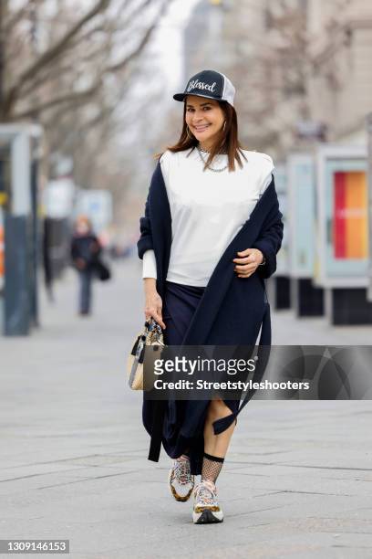 Model and DJane Gitta Saxx wearing a white sweater pullover by Sonja Kiefer Studio, a dark blue wrap skirt by Sonja Kiefer Studio, a dark blue and...