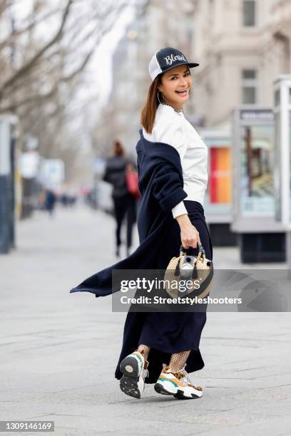 Model and DJane Gitta Saxx wearing a white sweater pullover by Sonja Kiefer Studio, a dark blue wrap skirt by Sonja Kiefer Studio, a dark blue and...