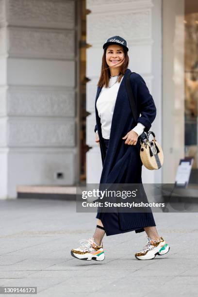 Model and DJane Gitta Saxx wearing a white sweater pullover by Sonja Kiefer Studio, a dark blue wrap skirt by Sonja Kiefer Studio, a dark blue and...