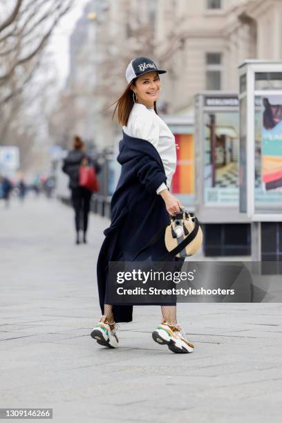 Model and DJane Gitta Saxx wearing a white sweater pullover by Sonja Kiefer Studio, a dark blue wrap skirt by Sonja Kiefer Studio, a dark blue and...