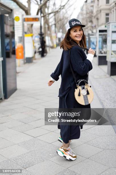 Model and DJane Gitta Saxx wearing a white sweater pullover by Sonja Kiefer Studio, a dark blue wrap skirt by Sonja Kiefer Studio, a dark blue and...