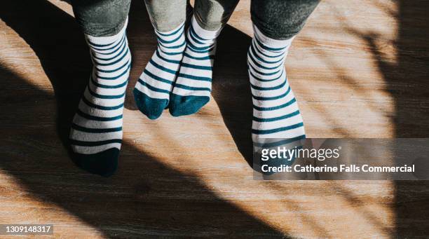 a small pair of feet between bigger feet in identical matching stripy socks - same person different outfits stock pictures, royalty-free photos & images