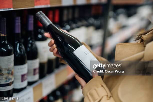 woman choosing red wine in liquor store - prosecco food stock pictures, royalty-free photos & images