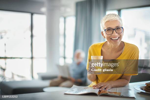 mature couple having a morning coffee at a kitchen counter. - senior reading stock pictures, royalty-free photos & images