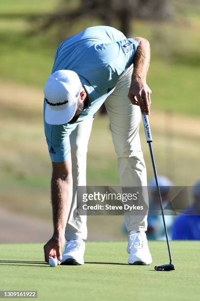 Dustin Johnson of the United States places his ball on the 18th green in his match against Robert MacIntyre of Scotland during the second round of...