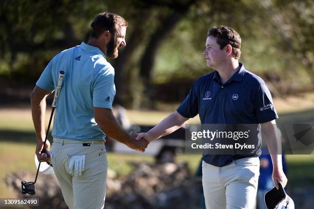 Dustin Johnson of the United States shakes hands with Robert MacIntyre of Scotland after a tie in their match during the second round of the World...