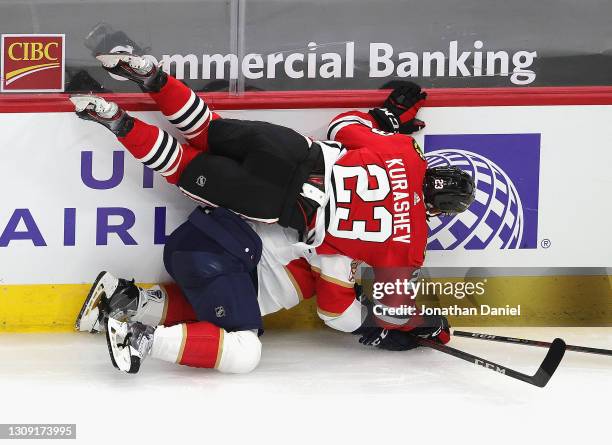 Philipp Kurashev of the Chicago Blackhawks collides with Radko Gudas of the Florida Panthers along the boards at the United Center on March 25, 2021...