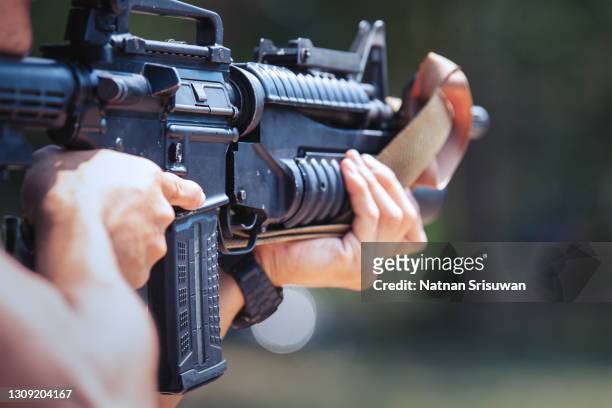 unrecognizable soldier holding machine gun - fusil fotografías e imágenes de stock