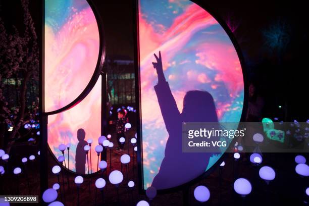 Tourists enjoy an immersive experience during the 2021 Beijing International Light Festival with the theme of 'Alive Together - Blue Space' at...