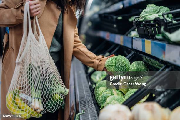 woman shopping for fresh organic fruits and vegetables in supermarket - herbruikbare tas stockfoto's en -beelden