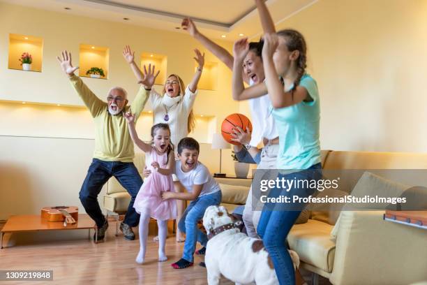 happy family members are spending wonderful time together while watching a  basketball game. - family tv pet stock pictures, royalty-free photos & images