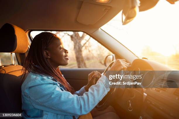 zijaanzicht van een vrouw die de auto drijft - car interior sunset stockfoto's en -beelden